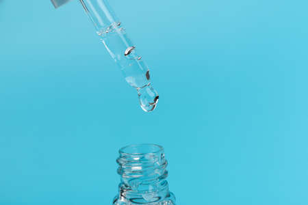 Cosmetic or medical glass bottle with pipette on blue background, in close-up. Skin care concept.の写真素材