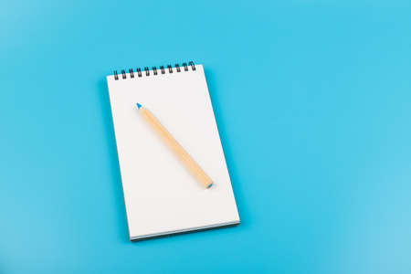multicolor pencils and blank notebook on blue background with copy spaceの写真素材