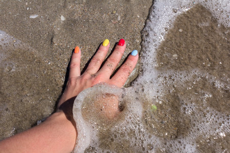 Colorful nail art on sand beach. Colorful nail polish. concept of the summer restの写真素材