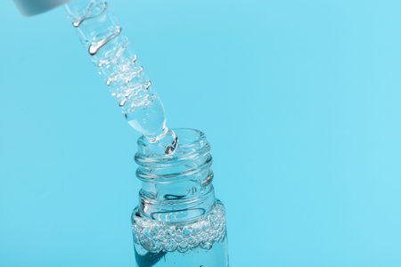 Cosmetic or medical glass bottle with pipette on blue background, in close-up. Skin care concept.
