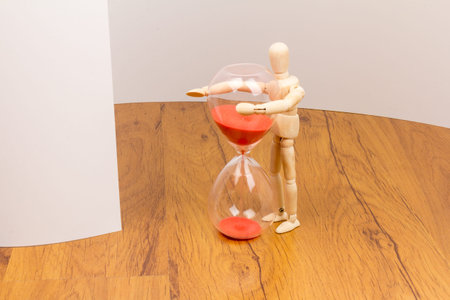 The wooden mannequin next towards the hourglass. keeping time