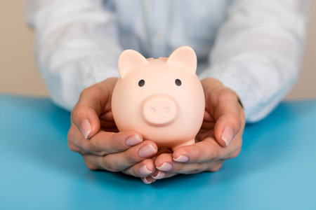 Piggy bank in hands on blue background, space for text. Finance, saving money