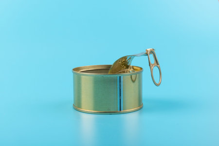 Opened pull cap of empty food can, isolated on blue background