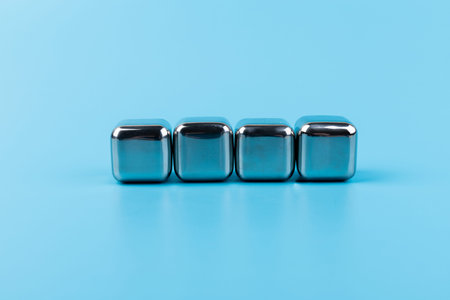 stainless steel ice cubes whiskey stones, isolated on blue background. Space for text.の写真素材