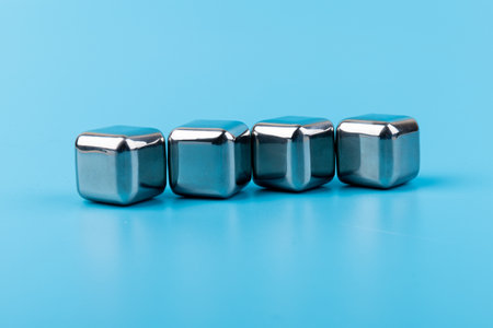 stainless steel ice cubes whiskey stones, isolated on blue background. Space for text.の写真素材