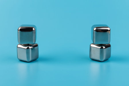 stainless steel ice cubes whiskey stones, isolated on blue background. Space for text.