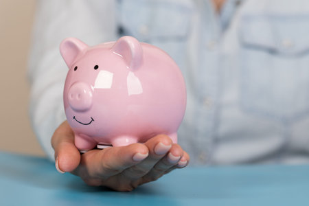 Piggy bank in hands on blue background, space for text. Finance, saving money
