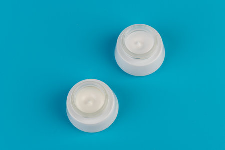 Container of moisturizing face cream on blue background. Fashion woman still life. Pop female things, medicine and cosmetic theme.の写真素材