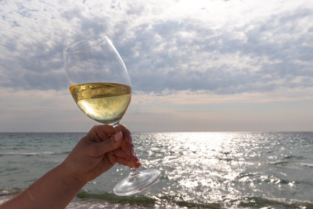 A glass of white wine. Wine against the backdrop of the sea coast and a sunny summer beach. Wine...
