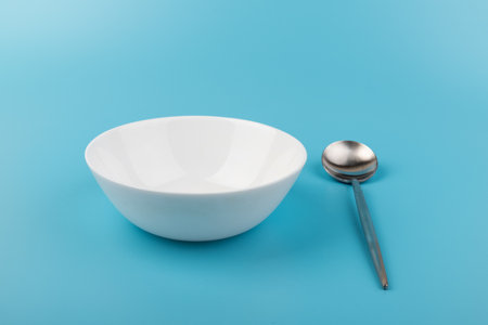 Empty plate with spoon on blue background. Top view. Kitchen Utensil.の写真素材