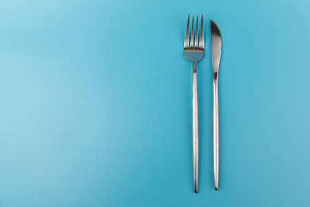 A fork and knife on blue background. Flat lay Dishes for breakfast, lunch or dinner. Top view. Kitchen Utensil.の写真素材