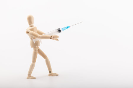 Wooden mannequin with syringe against white background. Coronavirus vaccination. Space for text.の写真素材