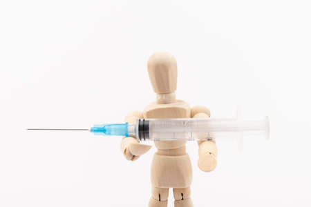 Wooden mannequin with syringe against white background. Coronavirus vaccination. Space for text.の写真素材
