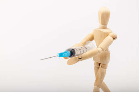 Wooden mannequin with syringe against white background. Coronavirus vaccination. Space for text.の写真素材
