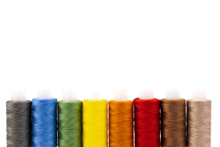 Sewing threads of different colors on reels on white background. Free space, close-up.の写真素材