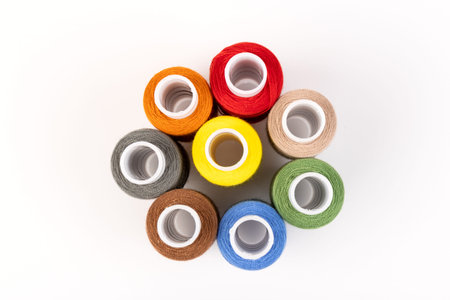 Sewing threads of different colors on reels on white background. Free space, close-up.