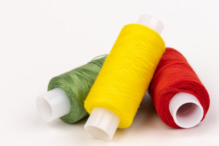 Sewing threads of different colors on reels on white background. Free space, close-up.