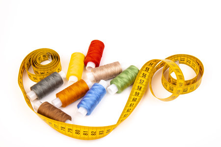 Detail of sewing thread with measure tape isolated on white background. Accessories of tailor or...