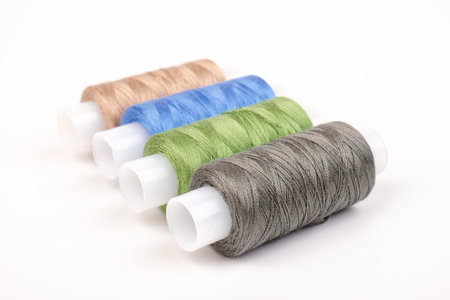 Sewing threads of different colors on reels on white background. Free space, close-up.