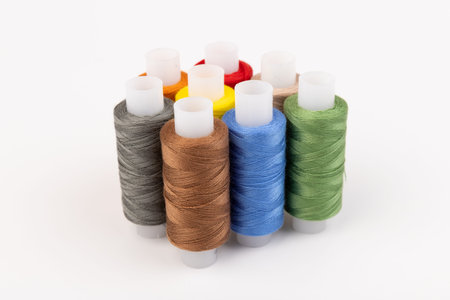 Sewing threads of different colors on reels on white background. Free space, close-up.