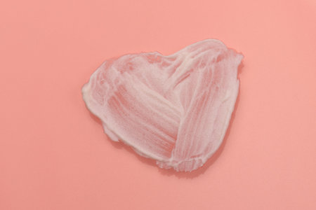 White smear of cosmetic cream isolated on pink background. Creamy foundation texture. Smear of face...