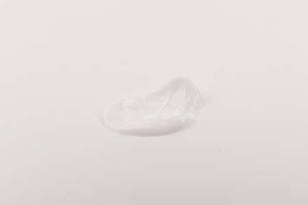 White smear of cosmetic cream isolated on light background. Creamy foundation texture. Smear of face cream. Texture of cream backgroundの写真素材