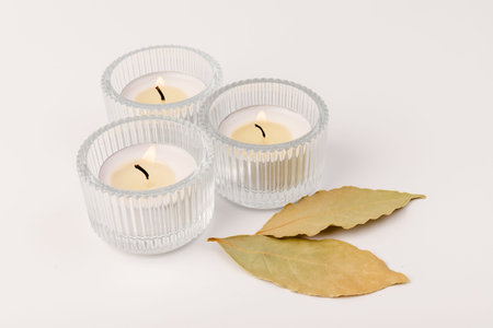 Scented candles with a dry leaf on a white background. Space for text.の写真素材