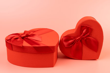 Red heart-shaped gift box with a red ribbon on pink background. Happy Valentine's Day. Anniversary.