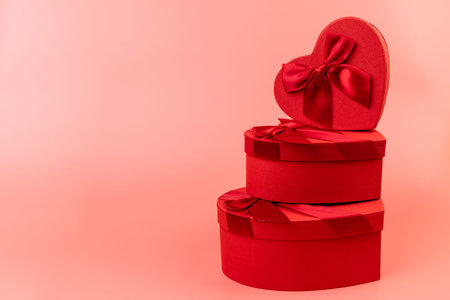 Red heart-shaped gift box with a red ribbon on pink background. Happy Valentine's Day. Anniversary.
