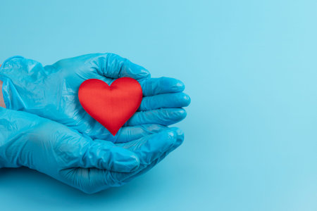 Female medicine doctor hands holding and covering red toy heart closeup. cardiology concept.
