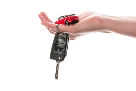 Hand holding keys and red car toy isolated on the white. The concept of buying a car