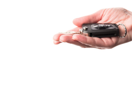 Black modern car key in hand isolated on white background. Close up car key fob.