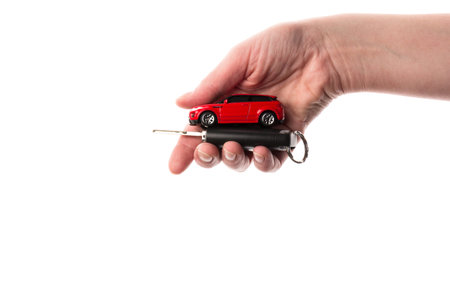 Hand holding keys and red car toy isolated on the white. The concept of buying a car