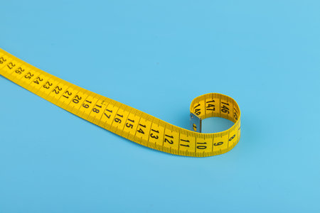 Yellow measuring tape on blue background. Space for text.