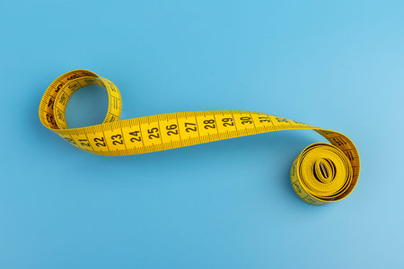 Yellow measuring tape on blue background. Space for text.