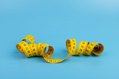 Yellow measuring tape on blue background. Space for text.