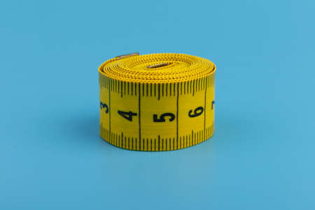 Yellow measuring tape on blue background. Space for text.の写真素材