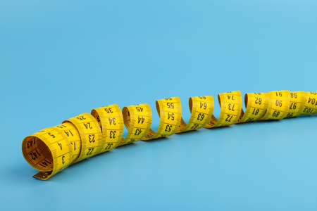 Yellow measuring tape on blue background. Space for text.の写真素材