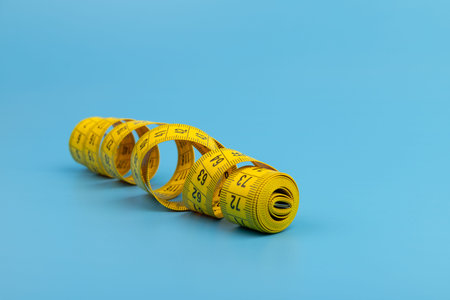 Yellow measuring tape on blue background. Space for text.