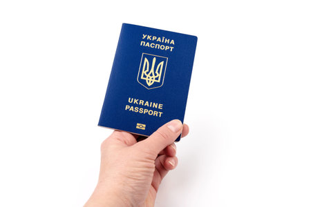 Human hand with Ukrainian international biometric passport closeup on white background. Document...