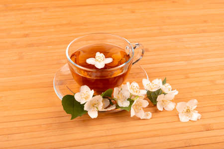 Cup of tea with jasmine, on bamboo mat, on bright backgroundの写真素材