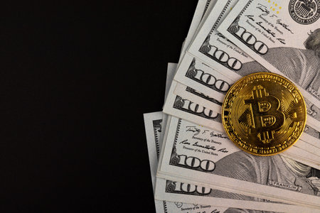 A symbolic coins of bitcoin on banknotes of dollars. Exchange bitcoin cash for a dollar. Black...