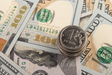 Coin with the inscription in Russian Ruble on the background of one hundred dollar bills. The fall...