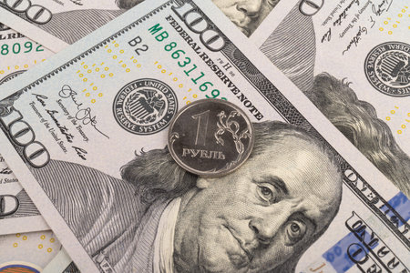 Coin with the inscription in Russian Ruble on the background of one hundred dollar bills. The fall...