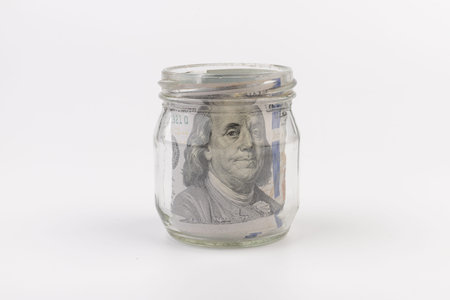 Paper money American dollars in glass jar label a coin as a variant of saving money.の写真素材