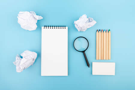 Paper balls, magnifying glass and color pencils over blank white sheet of note book - Creativity crisis concept. Creativity problems.の写真素材