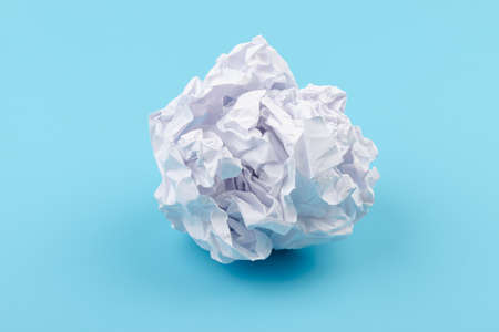 A piece of crumpled white paper on a blue background. Creativity crisis concept.の写真素材