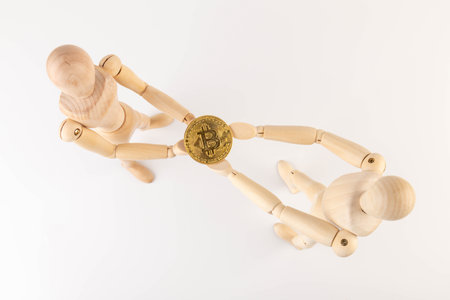 Cryptocurrency. Wooden mannequin holding bitcoin on white backgroundの写真素材