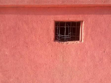 Old broken rusty window and red wallの写真素材