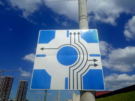 Road sign indicating the direction of movement in the city. Blue sky with white clouds.の写真素材